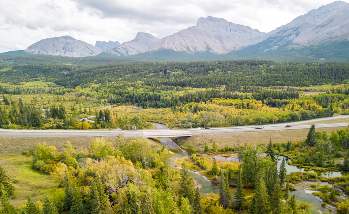 A scenic view of a road leading to a bridge over a river in the Crowsnest Pass.