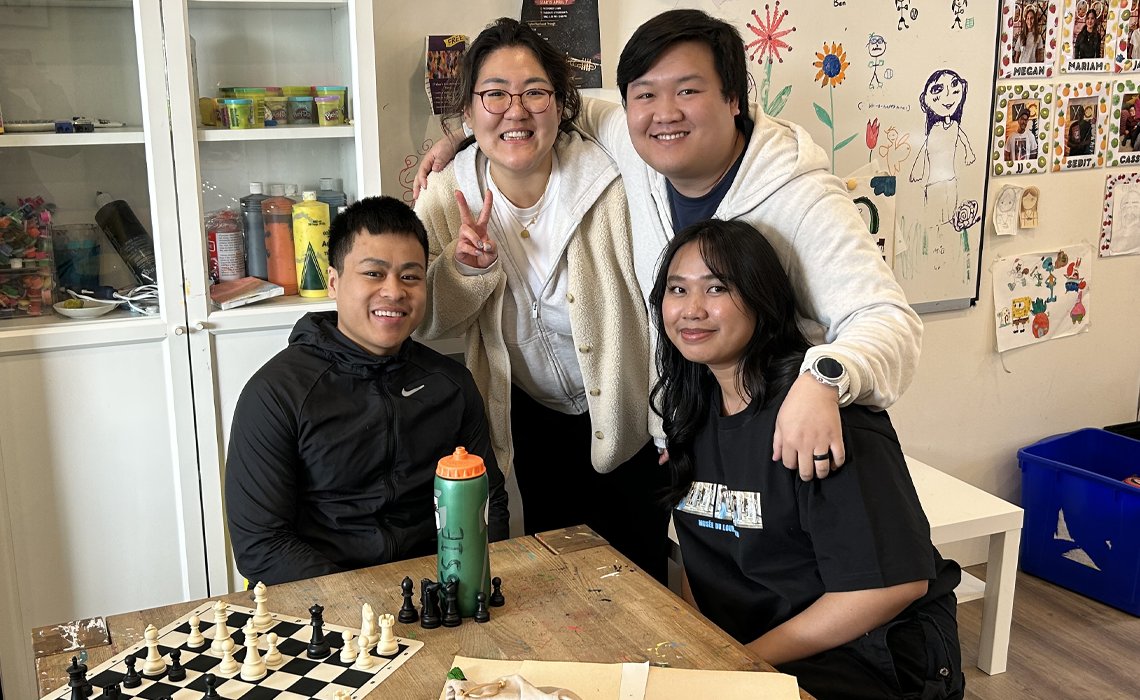 A group of MRU students seated around a table; smiling. 