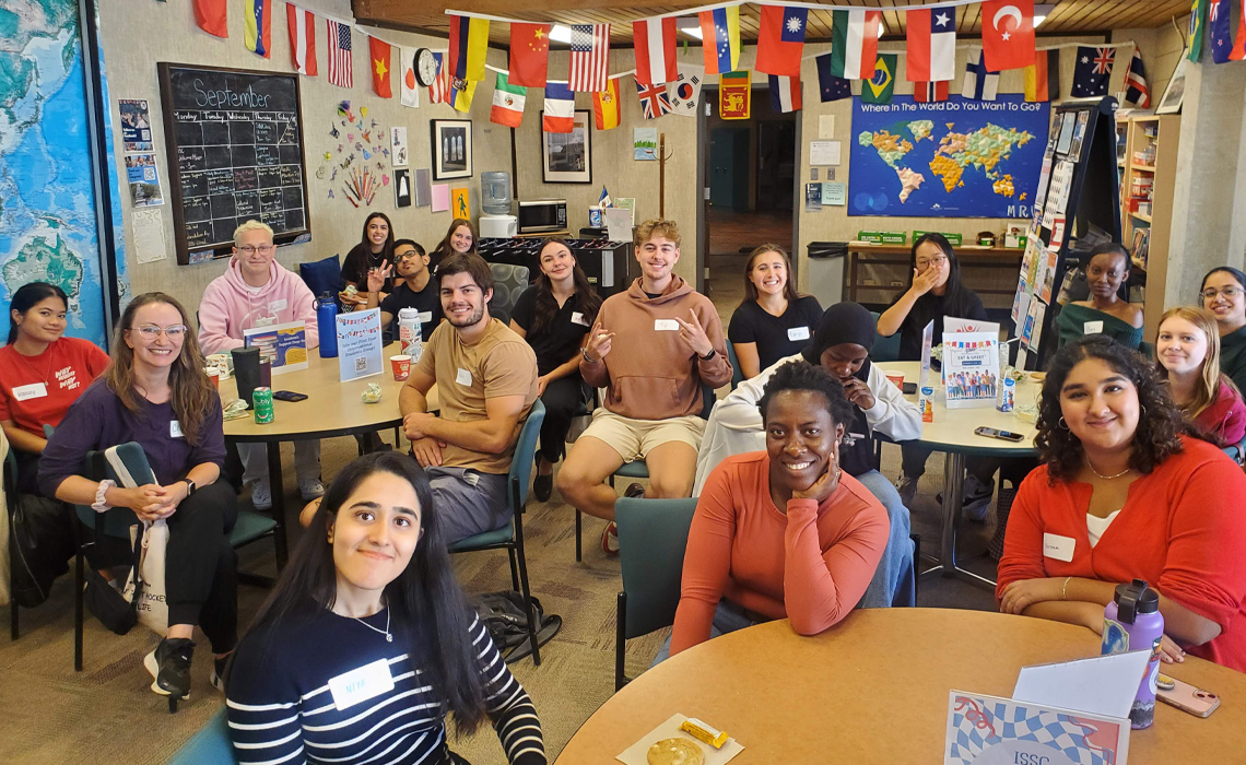 People sitting at tables in the Global Student Lounge.