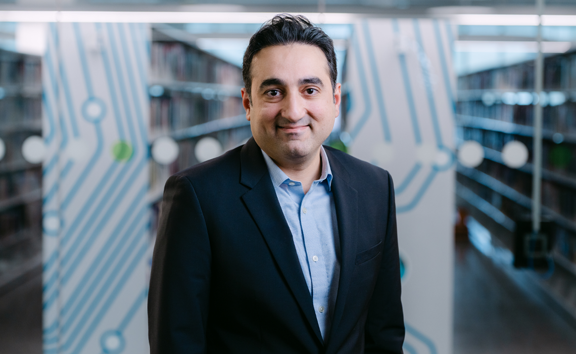 Dr. Hadi Fariborzi, PhD, smiling while standing in the Riddell Library and Learning Centre.