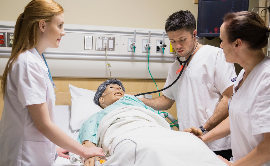 A group of students monitoring a medical manikin in the Simulation Learning Centre.