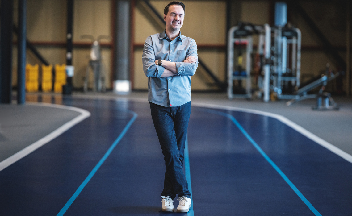 Jared Fletcher, PhD, stands with arms crossed on the upper level of the fitness centre at Mount Royal University.