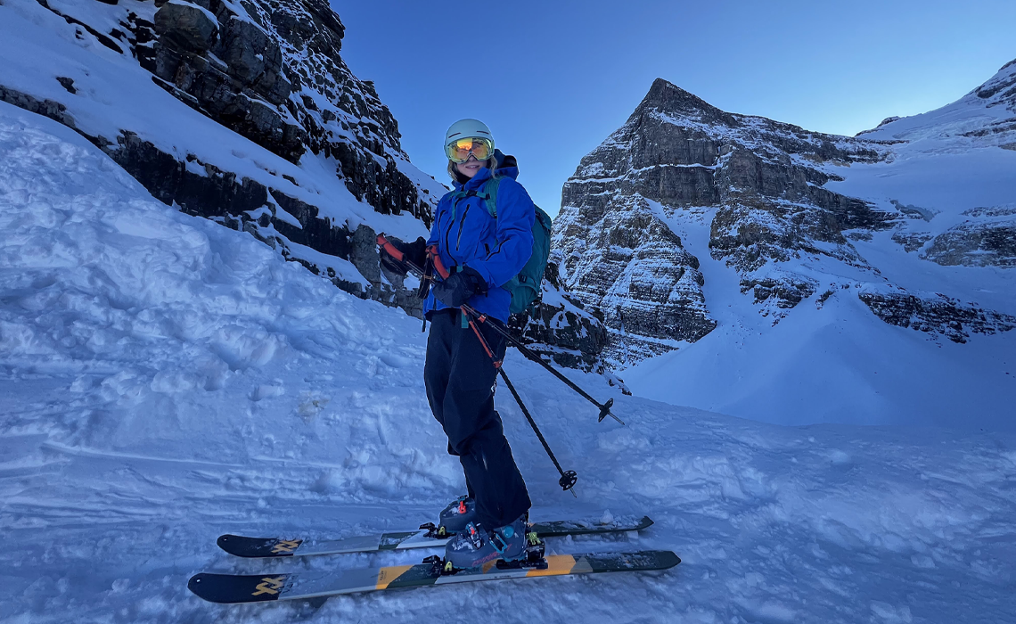 Jenna Sherrington in ski gear stands on a snowy slope, surveying the terrain before skiing down.