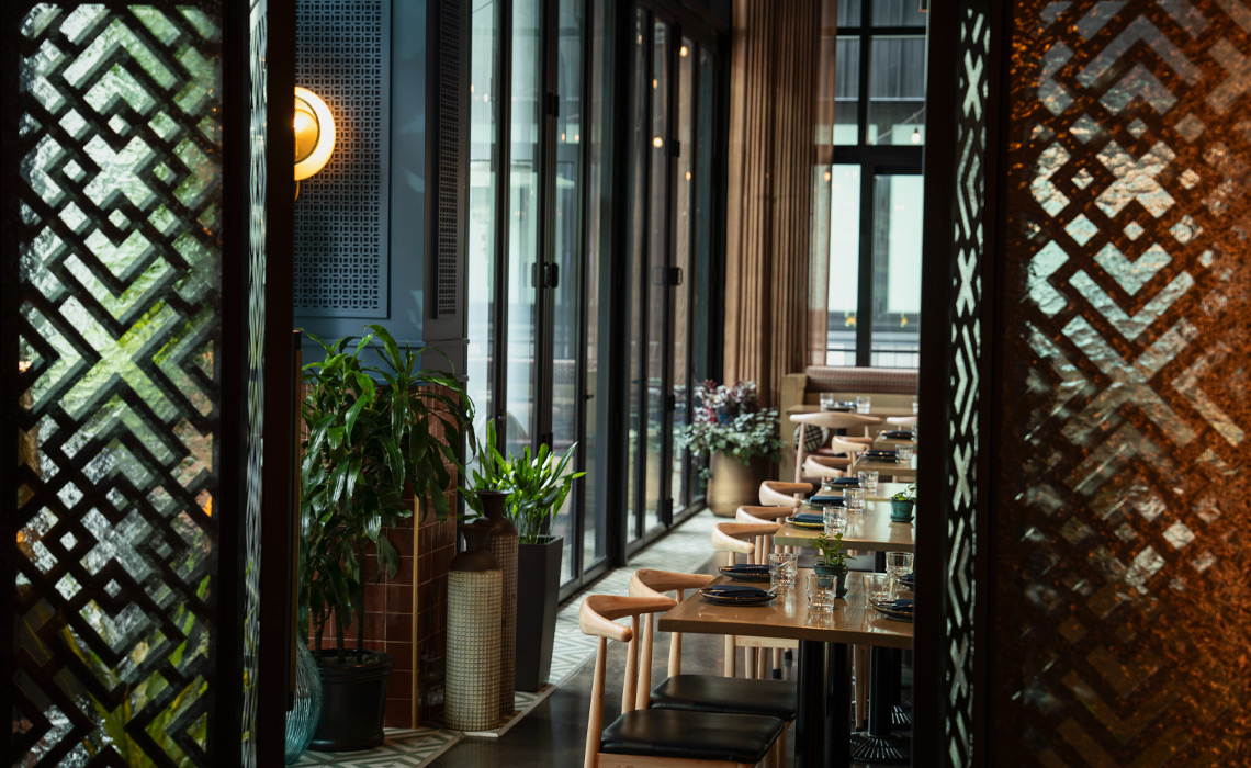 An interior view of Kama restaurant featuring wooden tables and chairs arranged for dining.