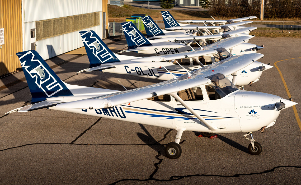 Several small aircraft lined up on a runway.