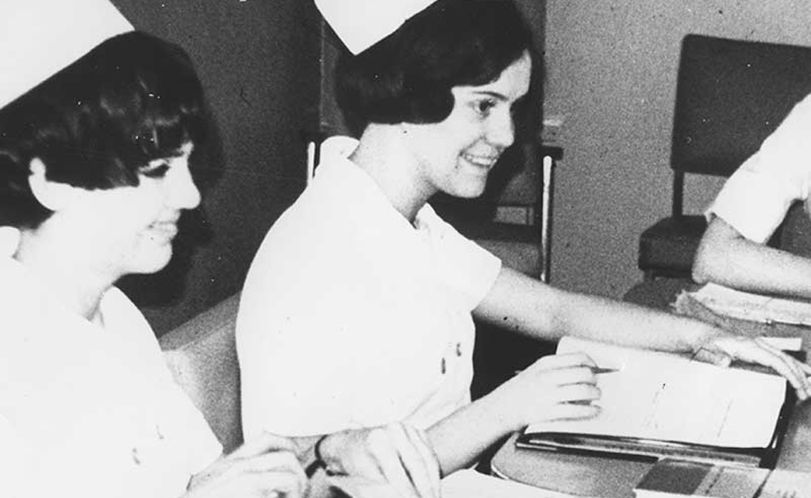 A group of nurses seated at a table, reviewing documents and discussing patient care strategies.
