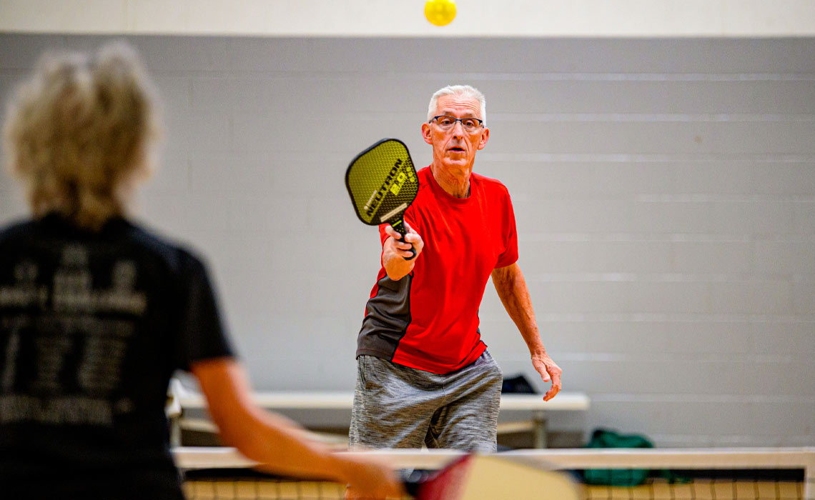 Two seniors play a leisurely game of pickleball.