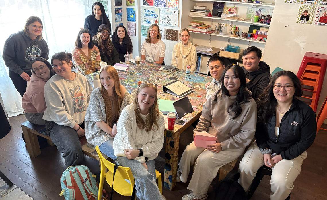 A group of MRU students seated around a table; smiling. 
