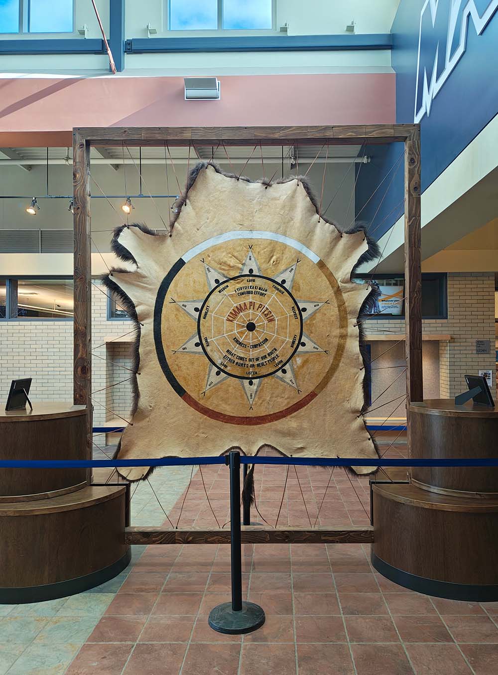The painted buffalo robe hanging in its frame at the Recreation entrance of Mount Royal University.