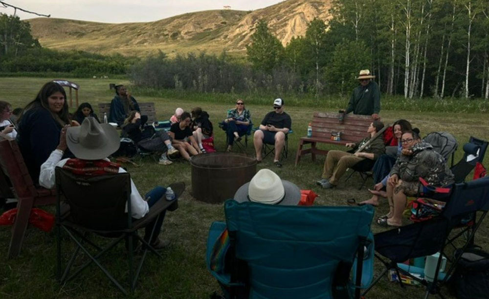 Students of the O’to po’pa Field School sitting around a campfire.