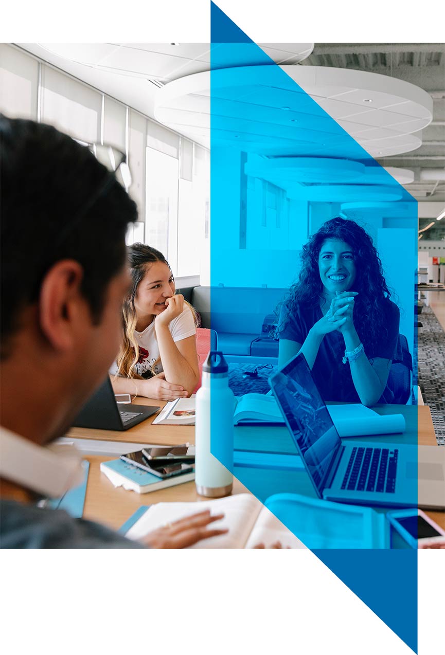 Photo of a group of students studying in the Riddell Library and Learning Centre. There is half of a chevron from the Mount Royal University logo overlayed over the photo in blue.