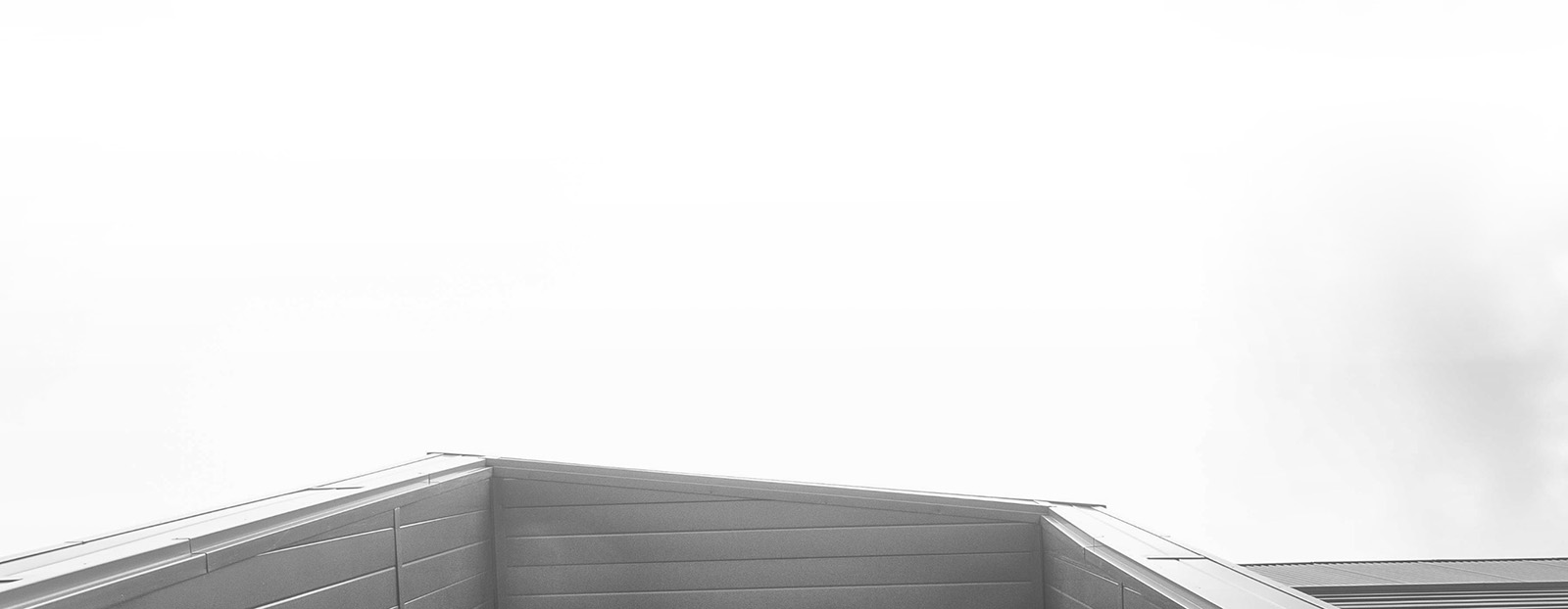 Black and white photo of the Roderick Mah Centre for Continuous Learning taken from below a roof overhang.