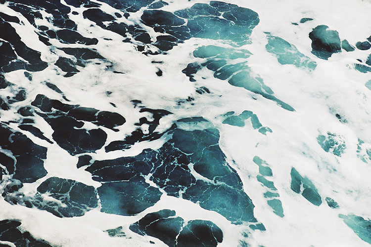 Top down photo of the ocean waves and seafoam.