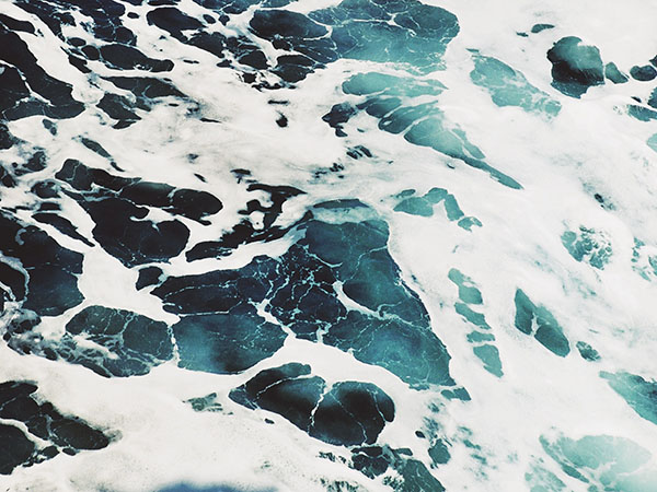 Top down photo of the ocean waves and seafoam.