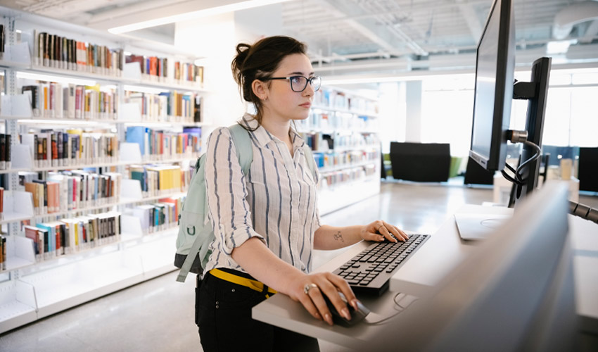 A student working on an assignment at a desk in the Riddell Library and Learning Centre.