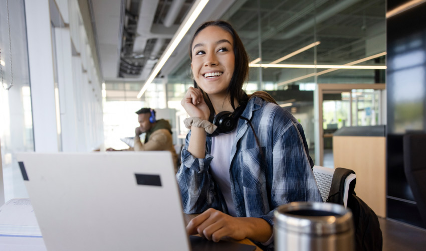 A smiling MRU student in the Riddell Library and Learning Centre.