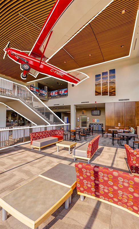 Photo of the atrium in the Bissett School of Business building. It is a high-ceilinged room with an airplane hung above a variety of seats.