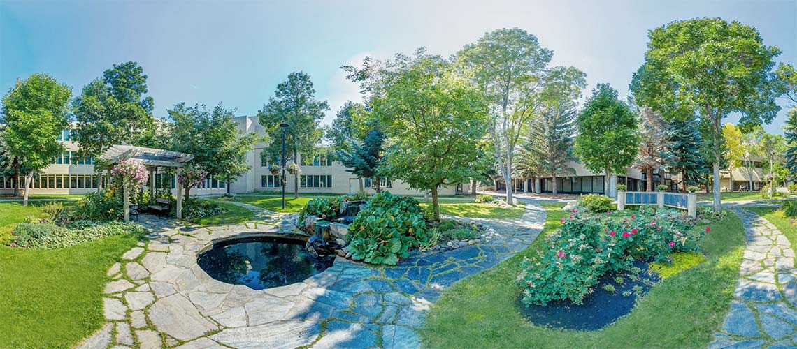 Photo of Mount Royal University's Centennial Sundial Garden. The tall stumps of trees are carves with feathers and a teepee is set up.