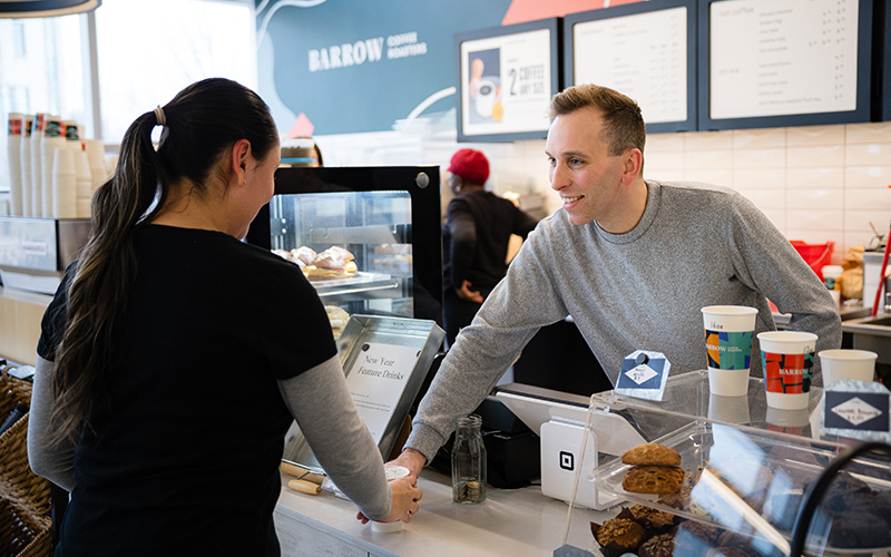 MRU Alum Ryan Wenger, serving coffee to a customer at his coffee shop, Barrow Coffee Roasters.