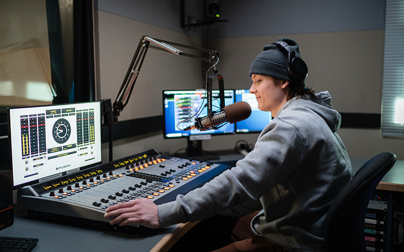 A broadcast media studies student mixing sound in a sound studio.