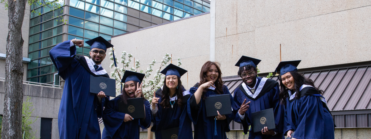 A group of new grads taking a celebratory photo out by the Charlton Pond