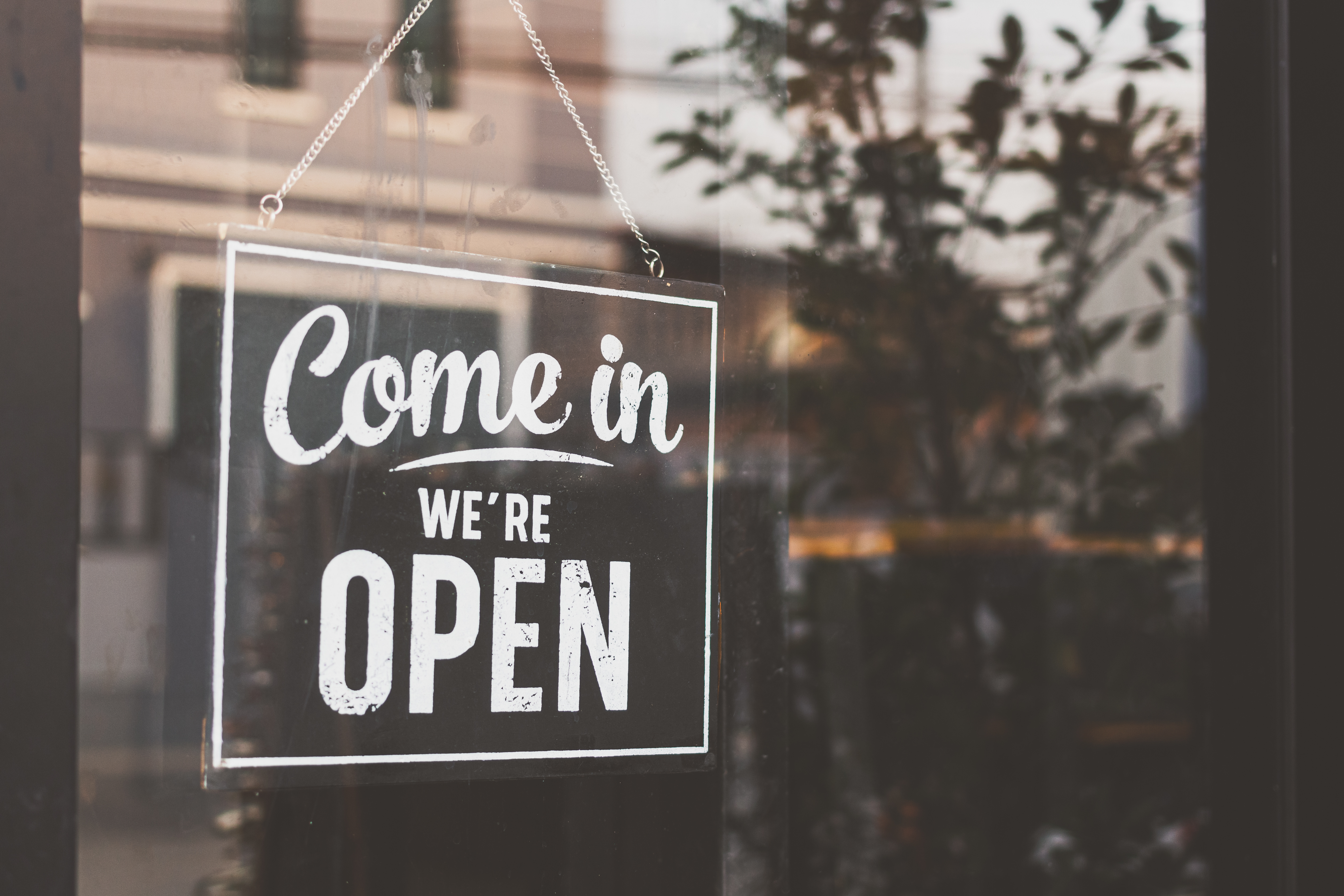Window of a business showing a'Come in. We're open' sign