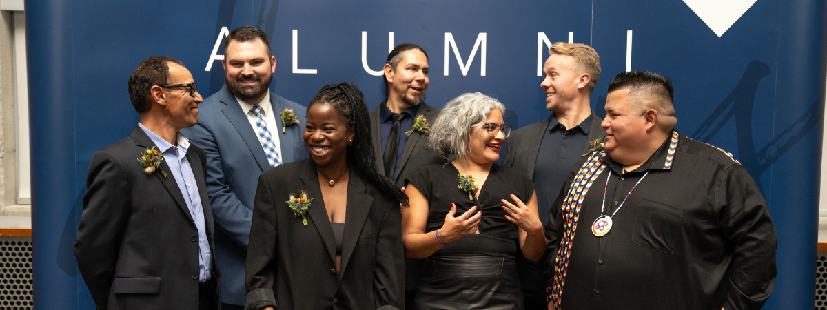 A group of alumni standing and talking in front of an MRU Alumni backdrop.