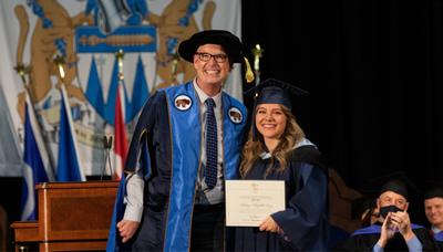 Photo of a graduate posing with President and Vice-Chancellor, Timothy Rahilly at convocation.
