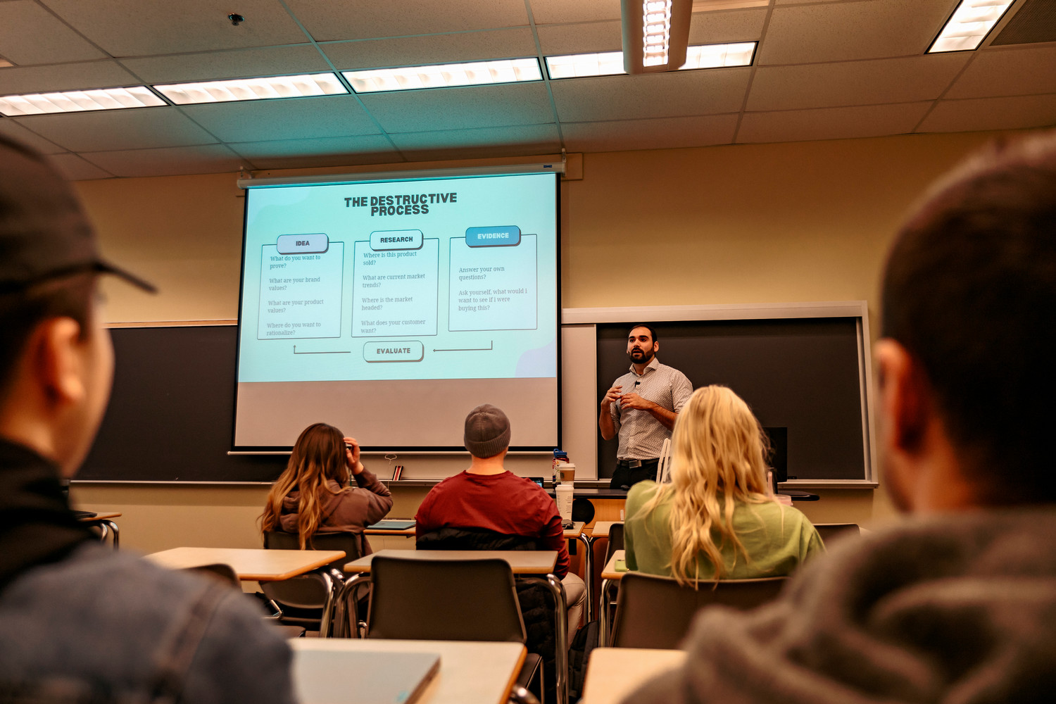 An alum giving a lecture to a classroom full of current MRU students.