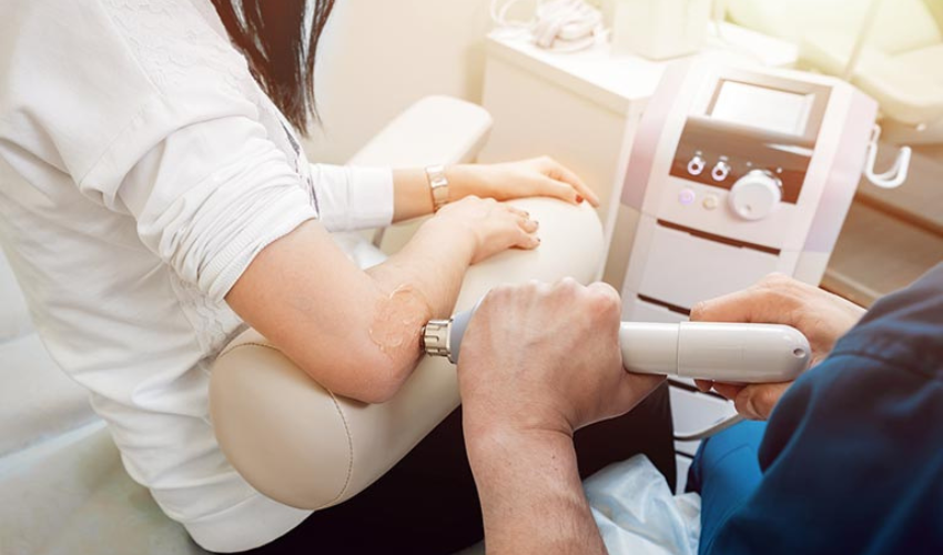 A practitioner using shockwave therapy on a patient's elbow