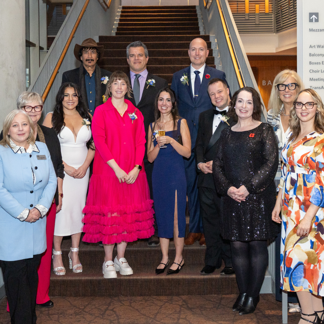 Winners of the Outstanding Alumni Awards posing in front of an Alumni banner