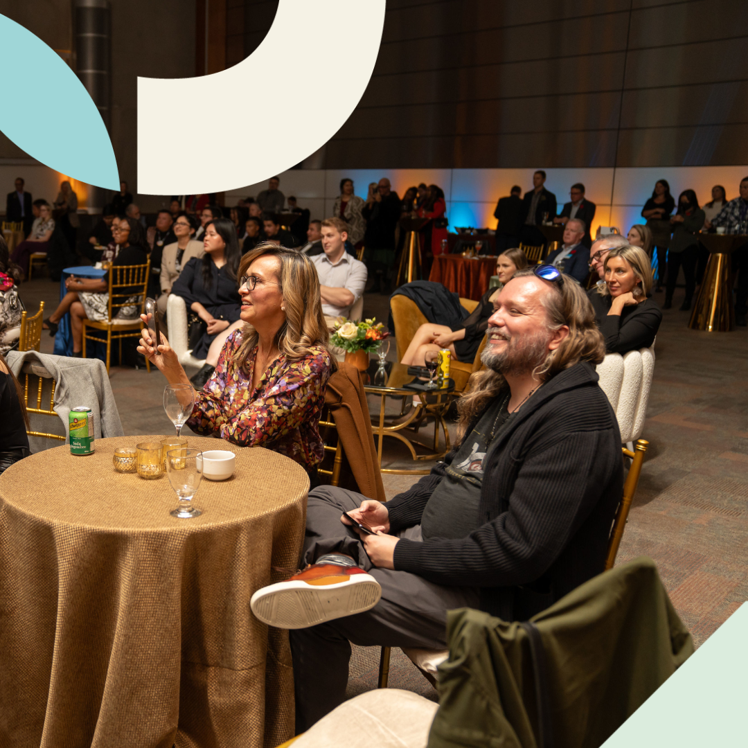 Attendees sit at banquet tables while listening to a presenter off-screen at the Outstanding Alumni Awards event.