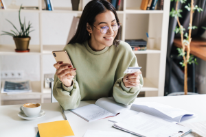 A woman looking at her ONECard while sitting in a home office.