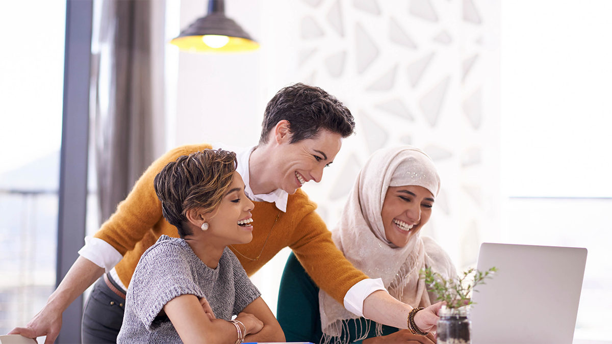 Three people laughing at something on a computer monitor.