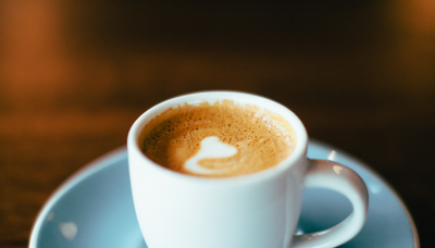 A coffee in a cup and saucer on a wooden table.