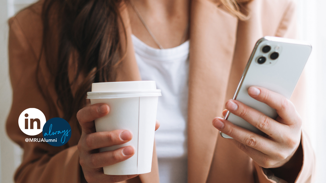 Close up of a person's hands holding a phone and coffee cup.