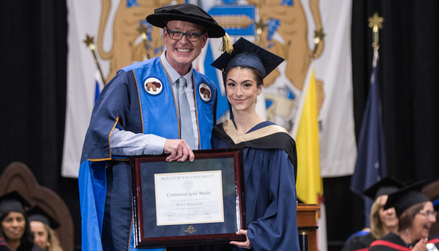 Dr. Tim Rahilly, PhD, President and Vice-chancellor of Mount Royal University, posing with a graduate on stage at Convocation.
