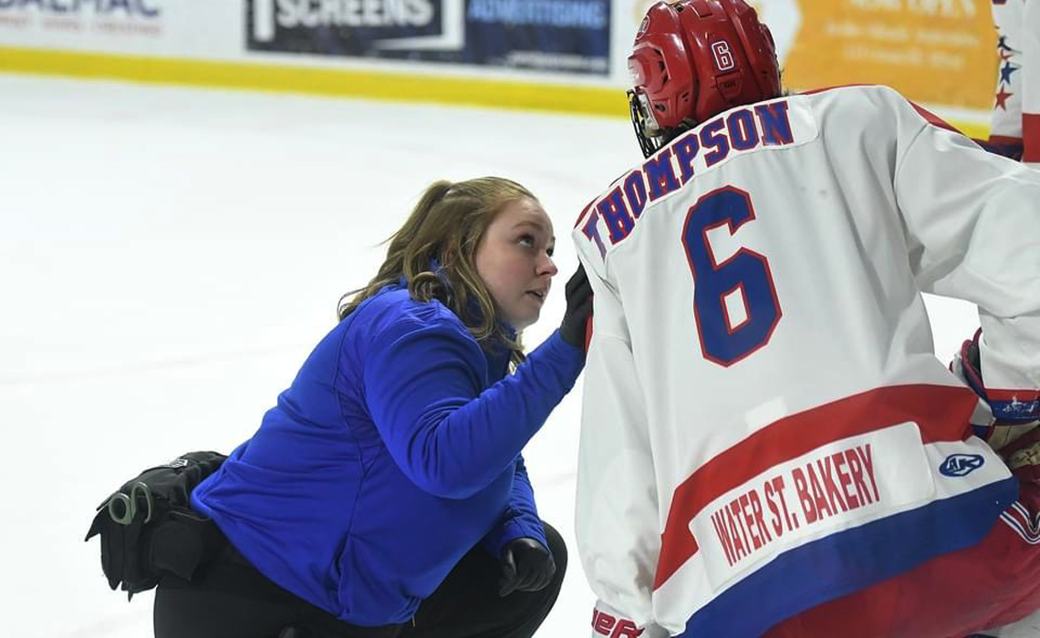 Alumna Megan Drouin talking to a hockey player just off the ice.