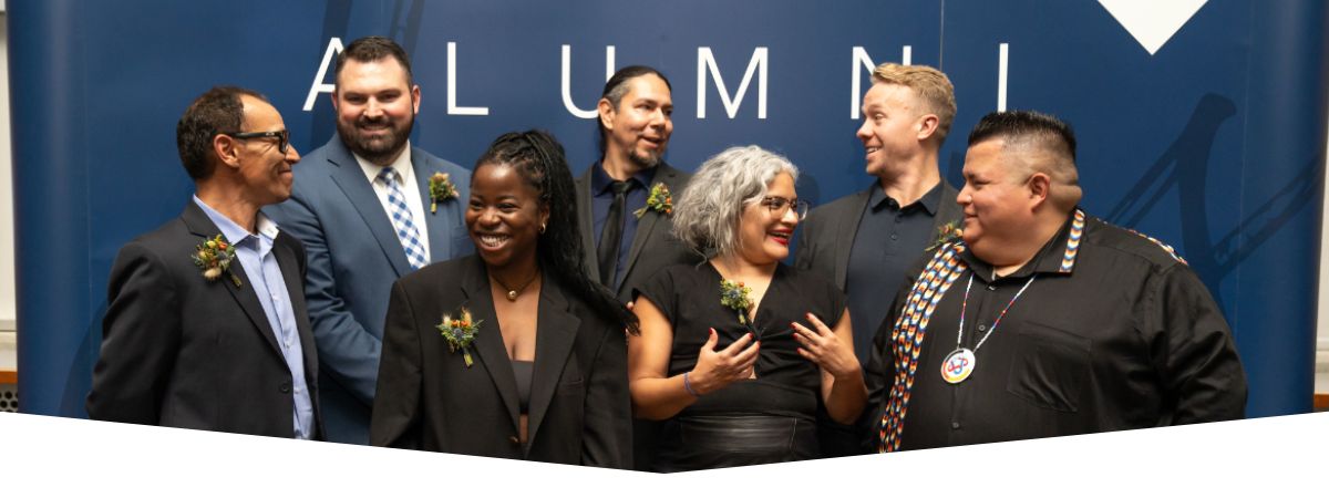 A group of alumni standing and talking in front of an MRU Alumni backdrop.