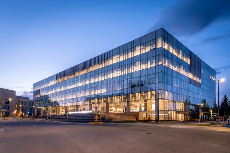 Exterior of the Riddell Library and Learning Centre at dusk. The lights glow bright in a darkening sky.