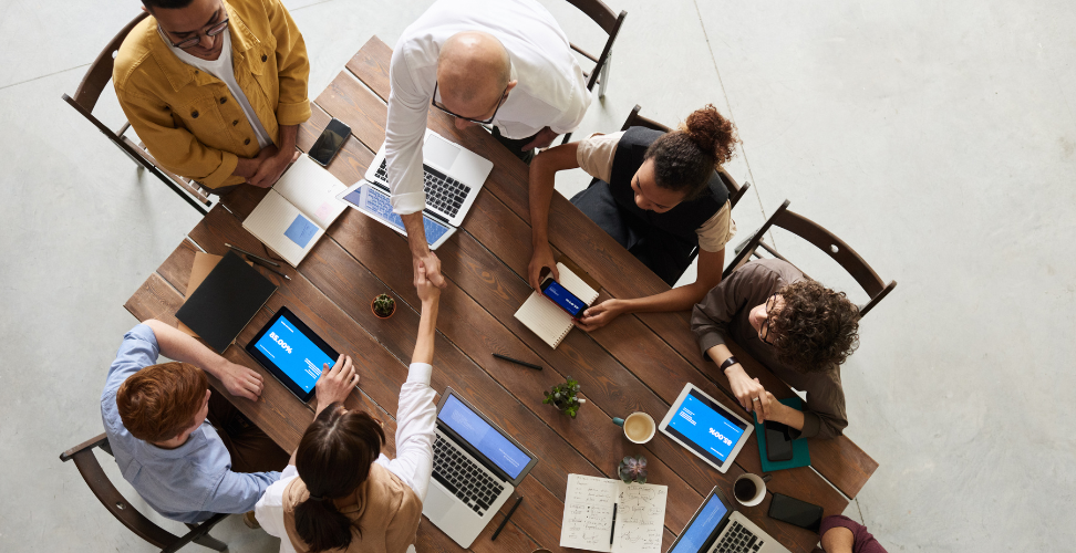 A table full of people working on laptops and collaborating.