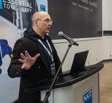 Adam McMath speaking at a podium