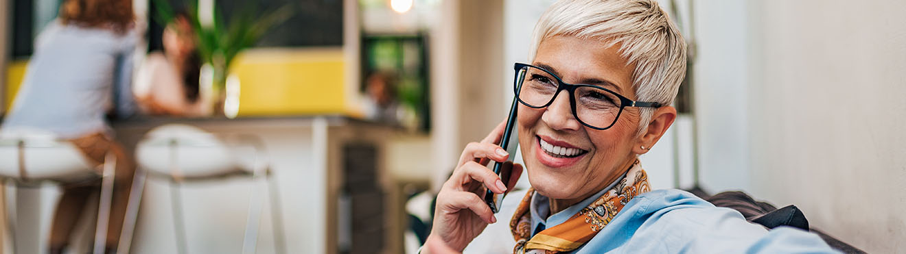 A middle-aged woman talking on a cellphone in a workplace.