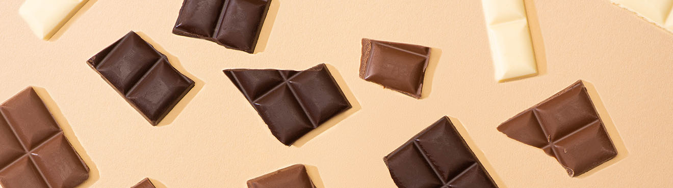 Pattern of broken pieces of chocolate on a peach background.