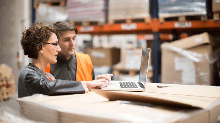 Professionals analyze inventory data in a warehouse.