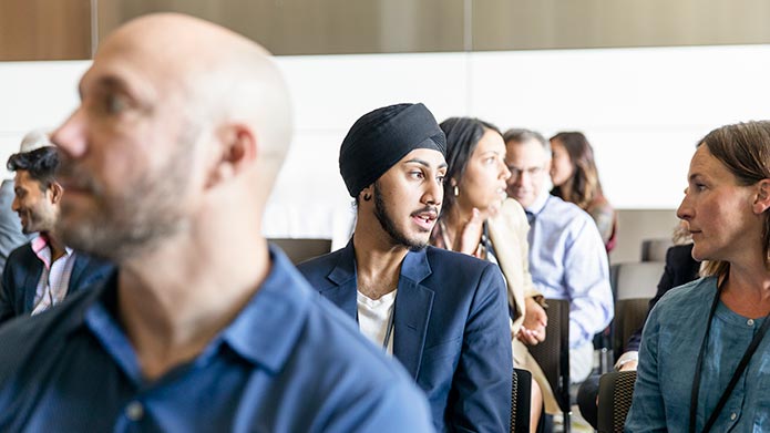 A group of professionals in an auditorium chatting.