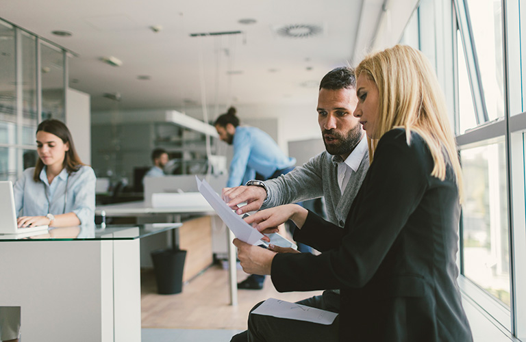 Two professionals discuss a business contract in an office setting.