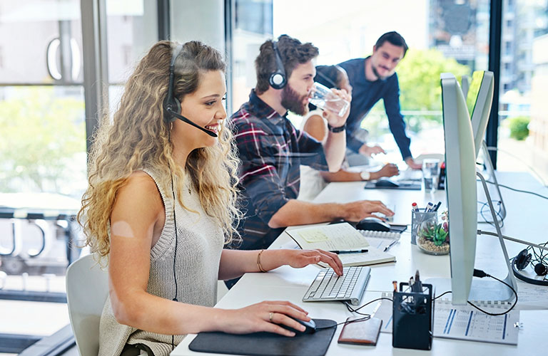 Customer service staff answer phones in an office environment.