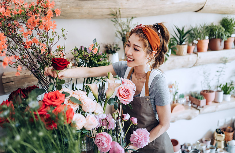 Owner of small floral business arranges flowers.