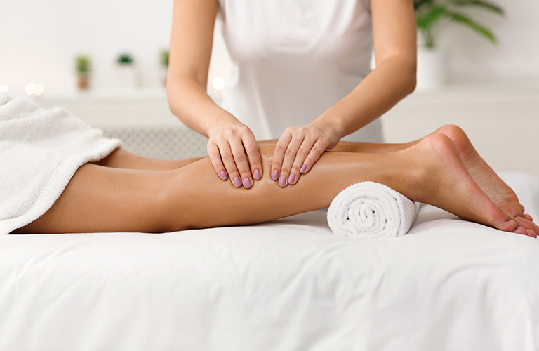 Massage practitioner massageing a calf of a client.